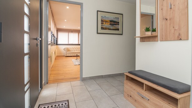 A hallway with a wooden bench, a framed painting, and a mirror on the wall.