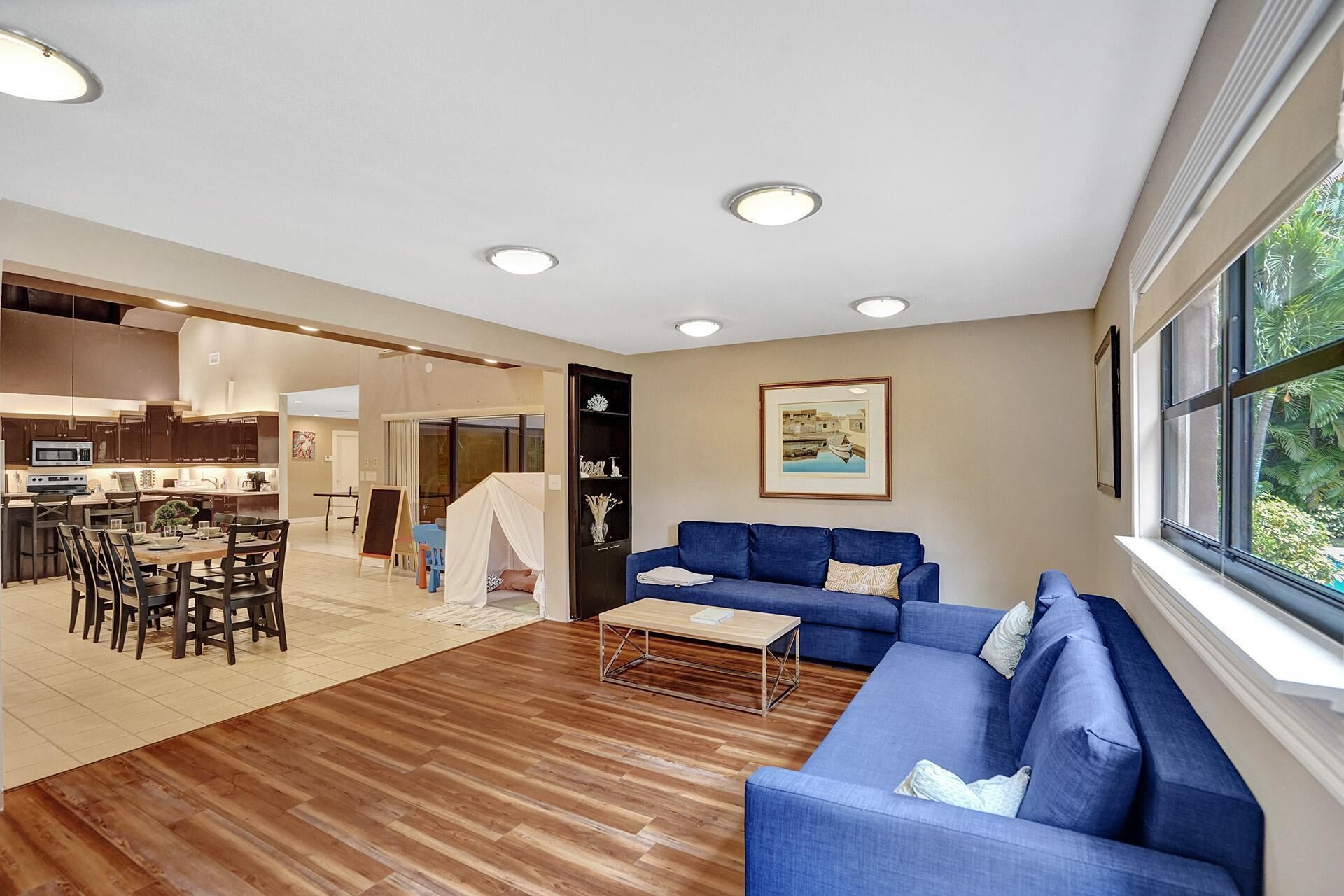 A spacious living area with a blue sofa, wooden flooring, and a dining area with a table and chairs.