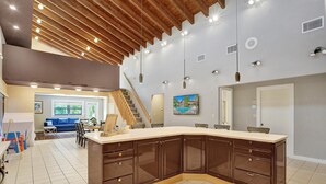 A modern kitchen with dark cabinetry, a large island, and a wooden ceiling.