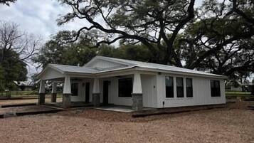 A single-story house with a gabled roof, a front porch, and a covered patio area.