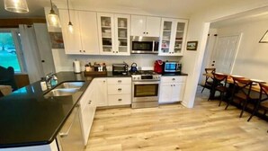 Una cocina moderna con armarios blancos, electrodomésticos de acero inoxidable y piso de madera.