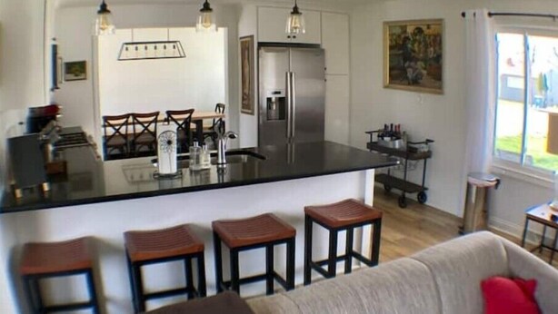 Una cocina moderna con una isla central, taburetes de bar e iluminación colgante.