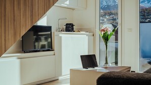 A modern kitchen with a flat-screen TV, a coffee machine, and a view of a mountain.