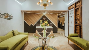 A modern lobby with a round glass table, green sofas, and a chandelier.