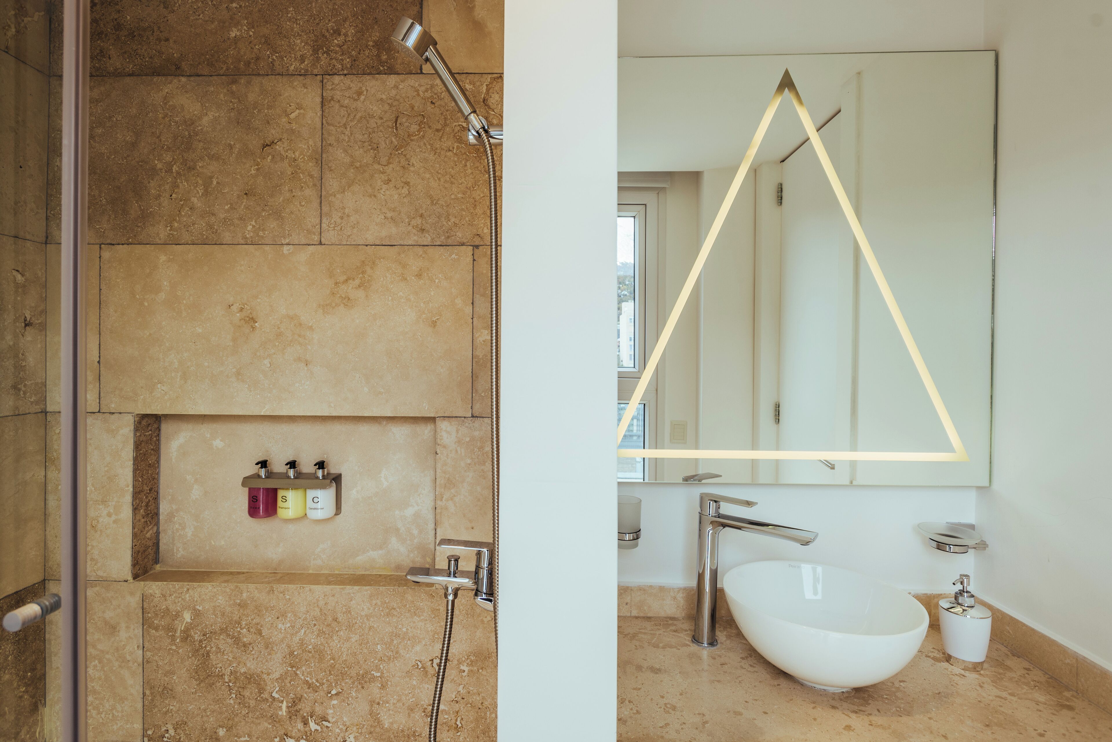A bathroom with a large mirror, a white sink, and a shower area.