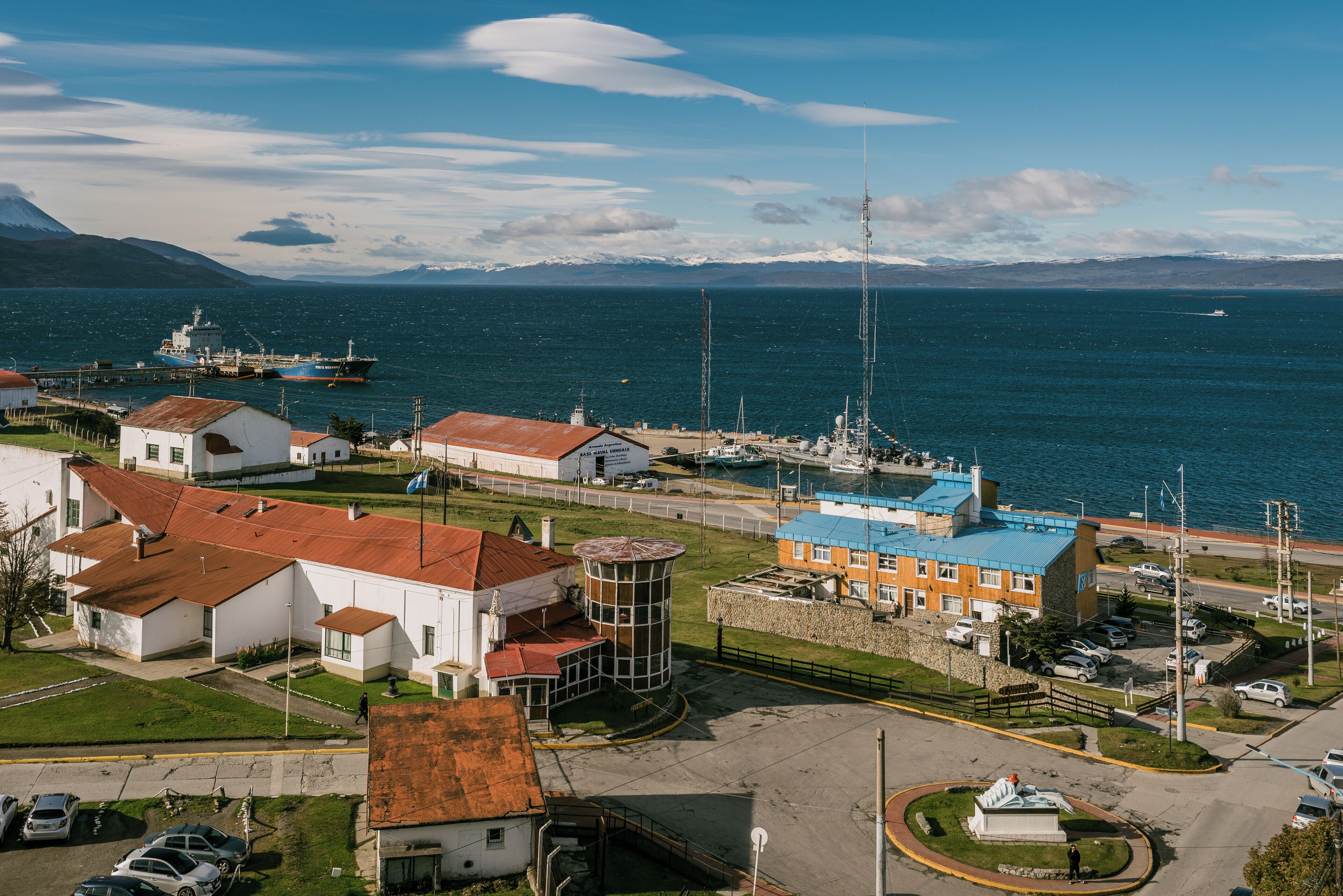Eine Küstenstadt mit einem markanten Leuchtturm, einer Anlegestelle mit einem großen Schiff und einer Mischung aus Wohn- und Geschäftsgebäuden.