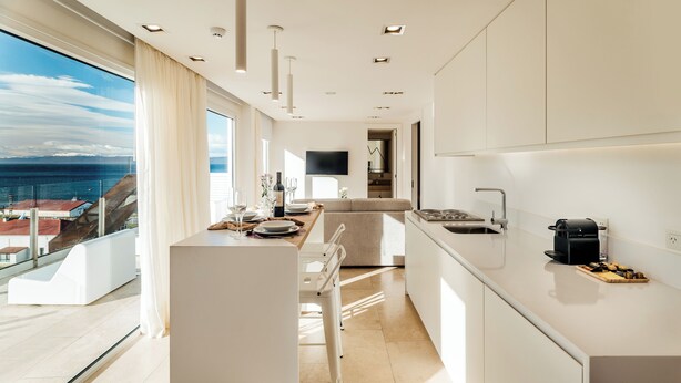 A modern kitchen with a view of the sea, a dining area, and a living space.