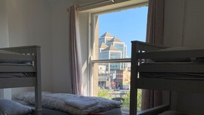 A room with bunk beds, a window with a view of buildings, and a table with water bottles. - City Centre Skyline - Private Room with shared bathrooms  (dublin)