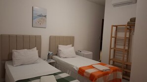 A hotel room with two beds, a bedside table with a lamp, a painting on the wall, and an air conditioning unit. - Fullano B&B (Rio de Janeiro)