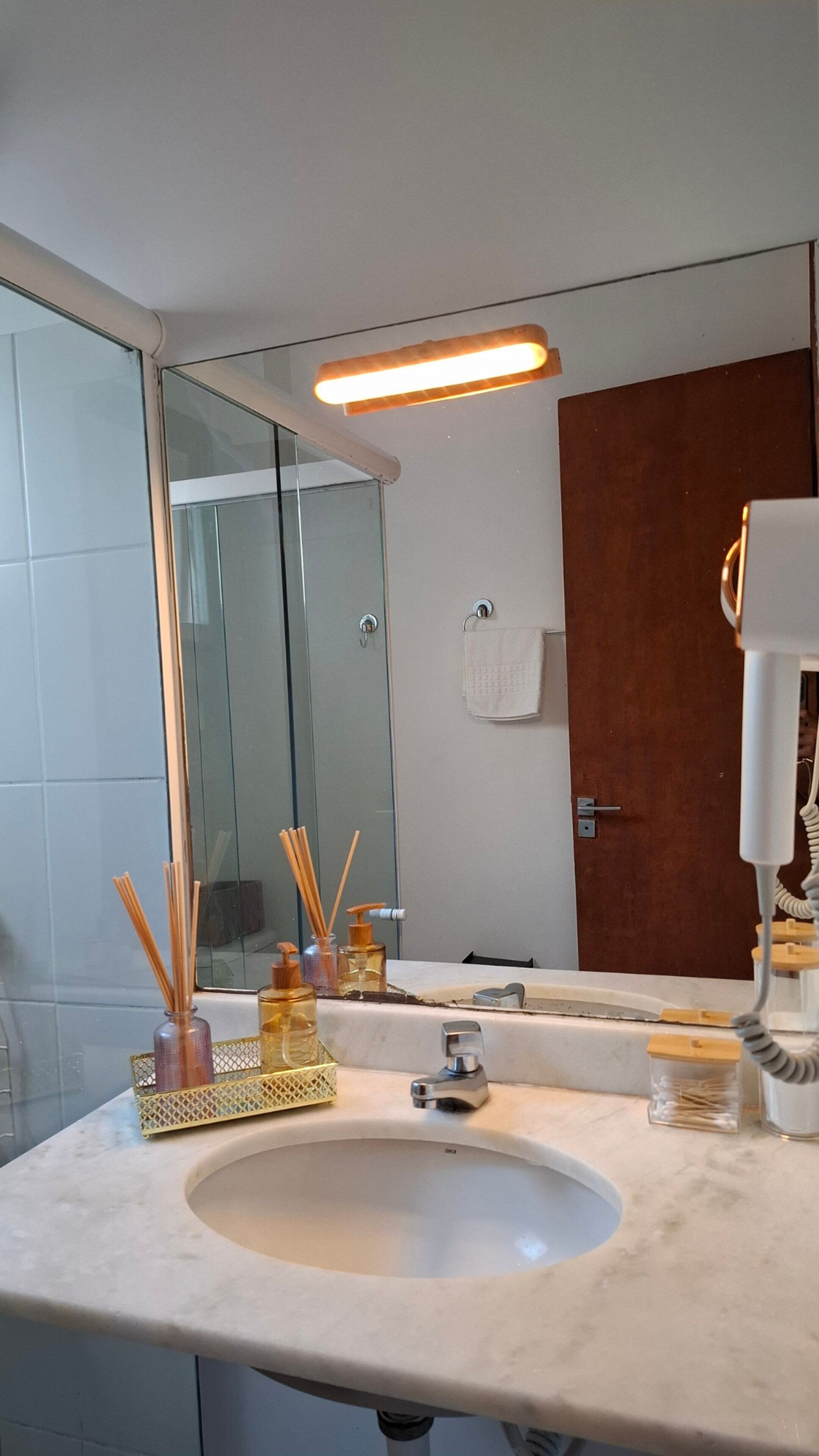 Un baño con lavabo, espejo y toallero.