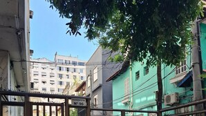 A gated entrance with a metal fence, cobblestone pavement, and buildings in the background. - Fullano B&B (Rio de Janeiro)