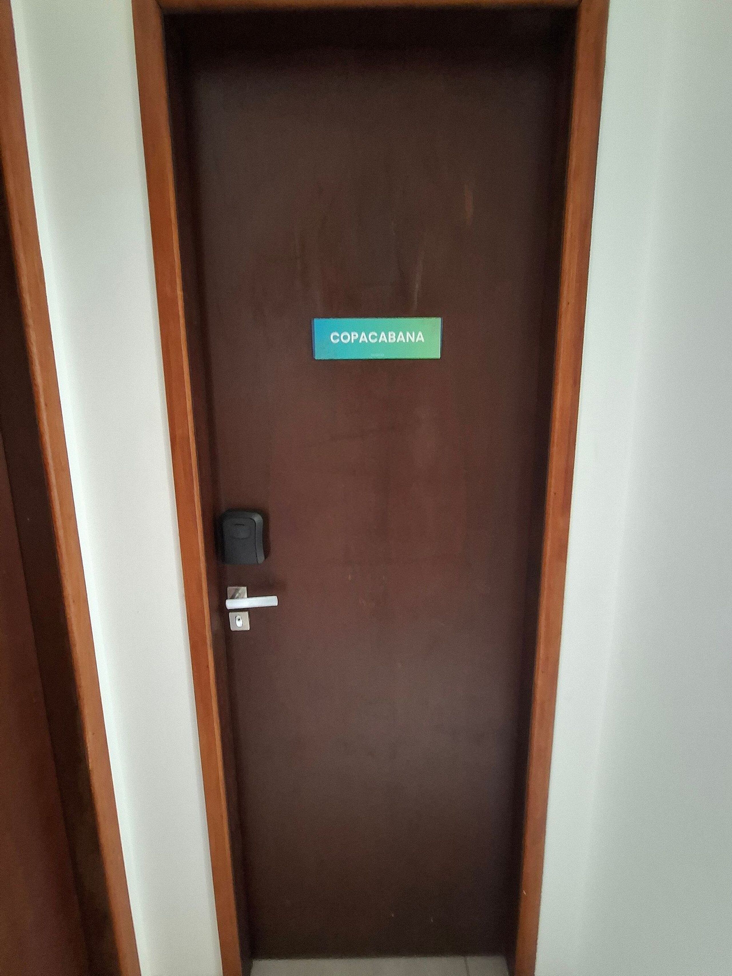 A brown door with a sign reading 'COPACABANA' and a door handle.