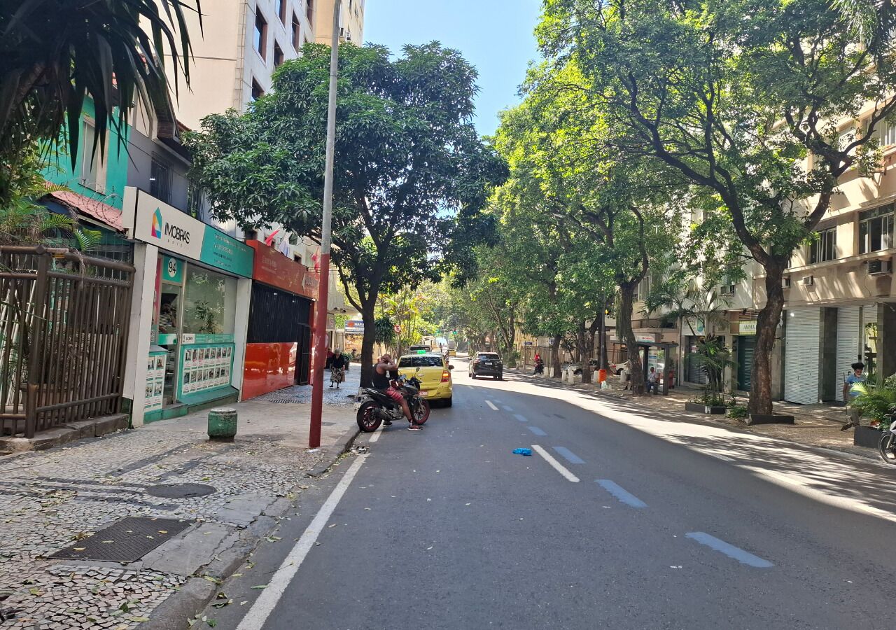 A street with buildings, a motorcycle, and a yellow car.