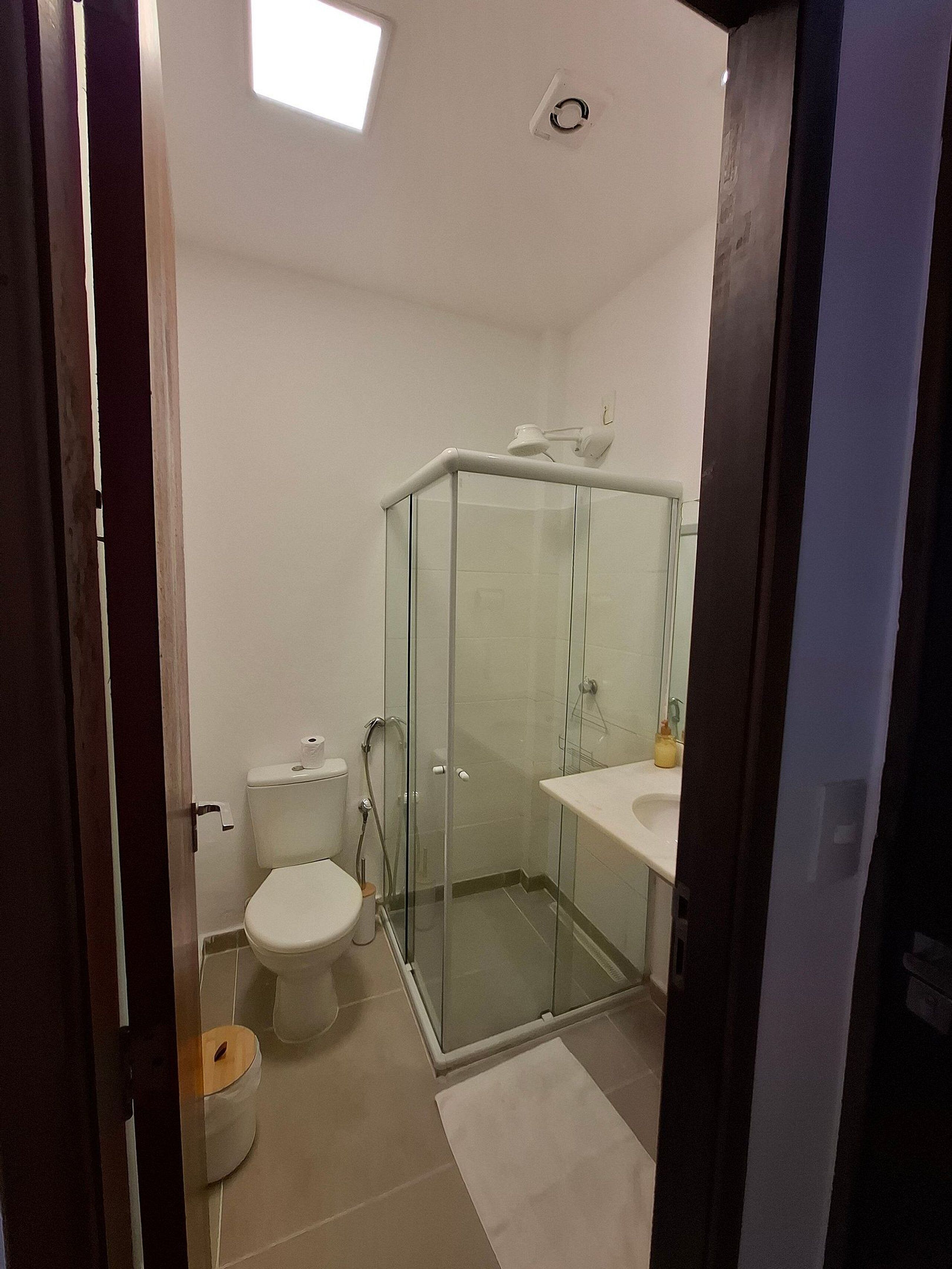 A bathroom with a glass-enclosed shower, a toilet, and a sink.