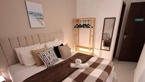 A neatly made bed with a checkered bedspread, a hanging coat rack, a bedside table, and a wall-mounted air conditioner. - Fullano B&B (Rio de Janeiro)