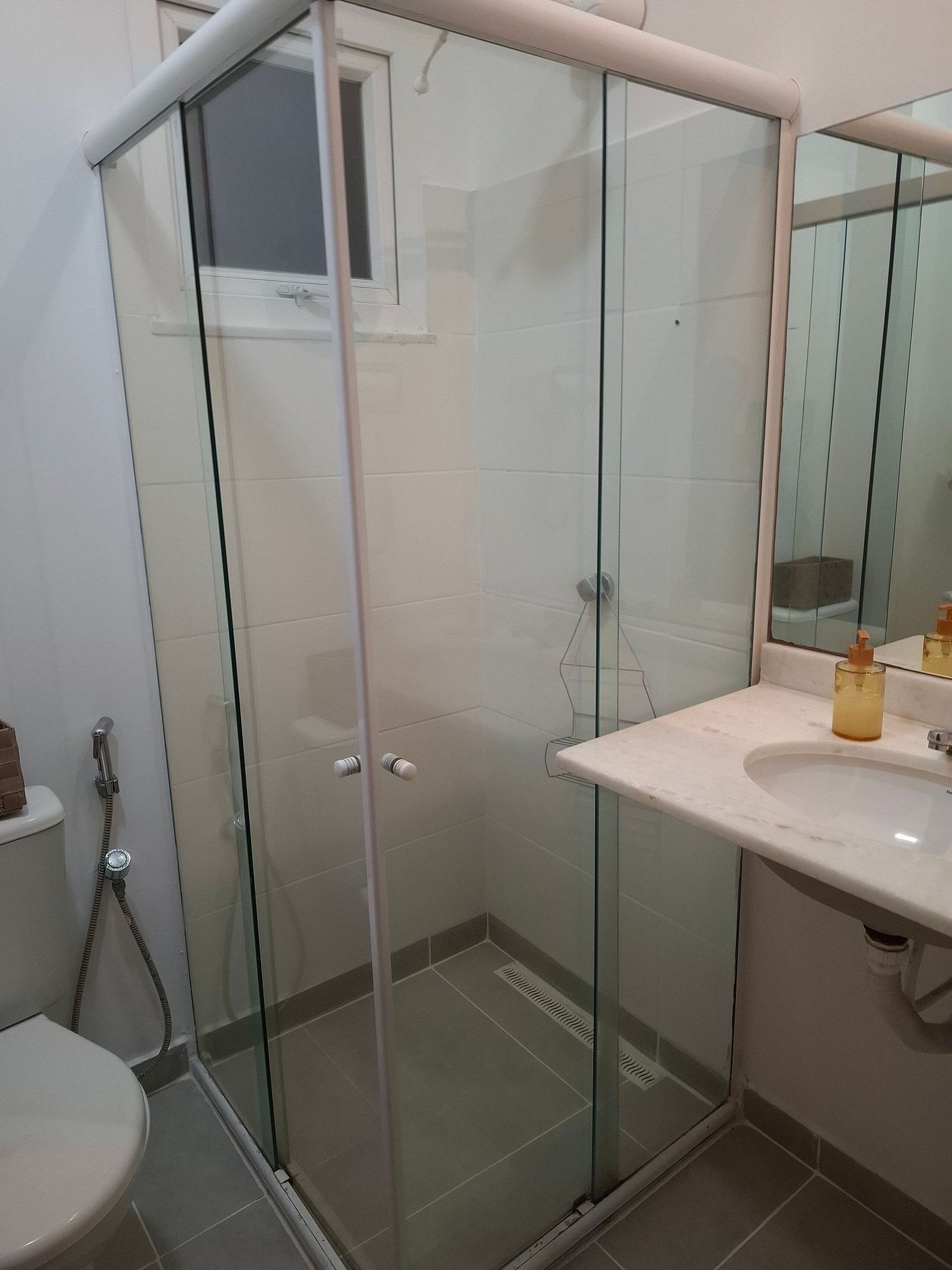 Une salle de bain avec une douche à parois de verre, des toilettes et un lavabo avec un miroir au-dessus.