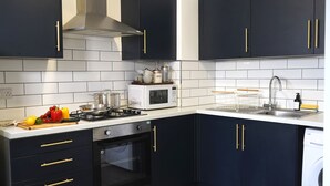 Een moderne keuken met donkere kastjes, een magnetron, kookplaat, oven en vaatwasser.