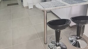 Cozinha moderna com arm ários brancos, micro-ondas, pia e dois banquetas.