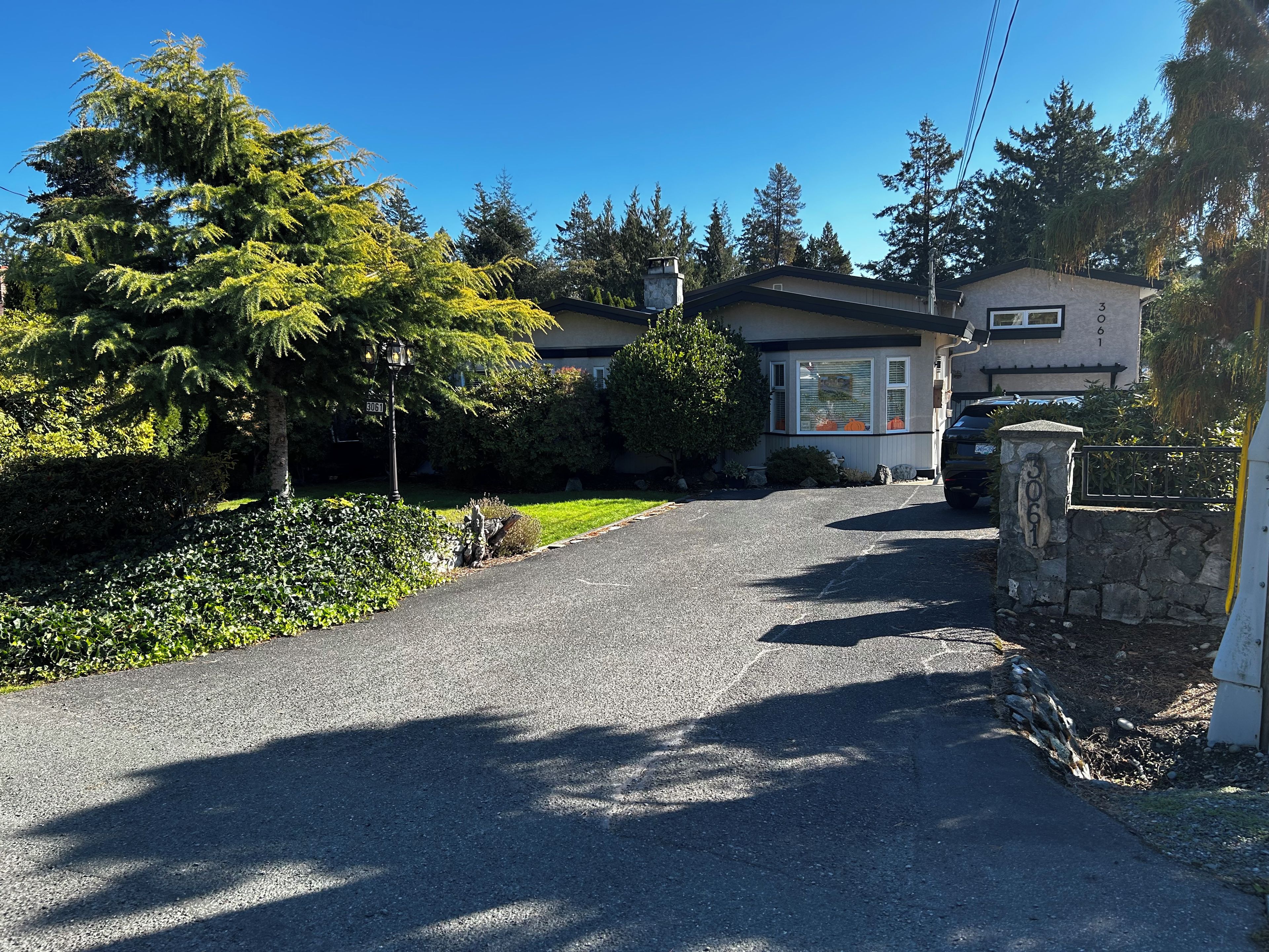 A residential driveway leading to a house with a stone wall and a mailbox.