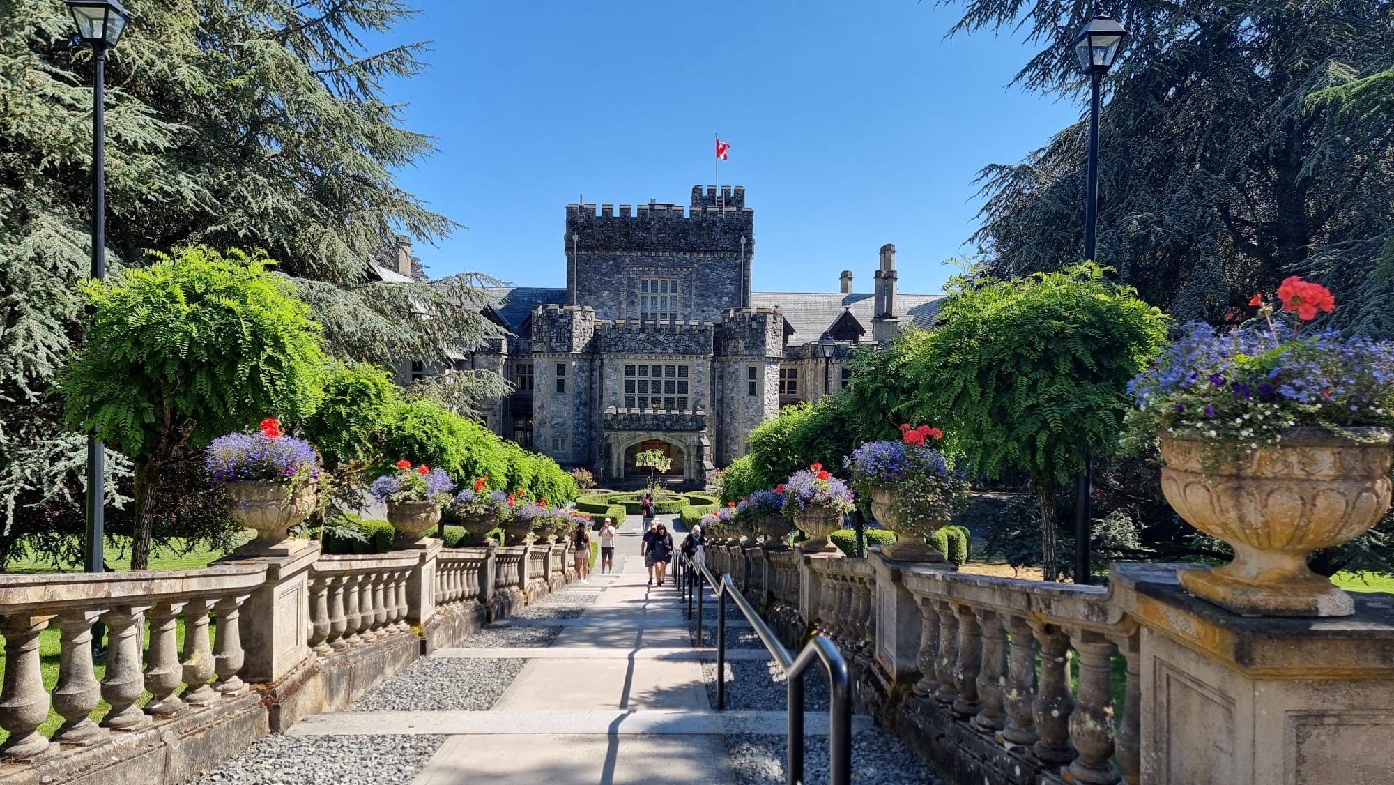 A castle-like building with a central entrance, surrounded by a formal garden with symmetrical pathways and large flower pots.