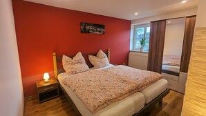 Een slaapkamer met een bed, nachtkastje en een raam met uitzicht op de omgeving.