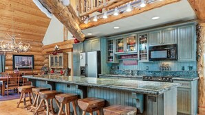 Una cocina rústica con vigas de madera, una isla grande con taburetes y un microondas.