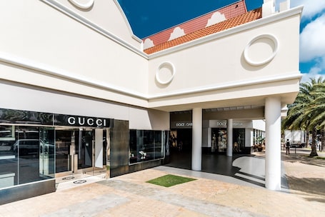 A modern building with a GUCCI store, a Dolce & Gabbana store, and a plaza with palm trees.. Central Boutique Hotel