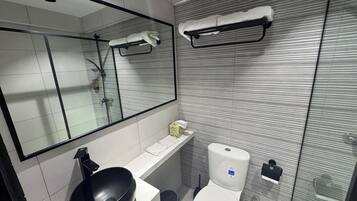 A modern bathroom with a black sink, white toilet, and a large mirror.