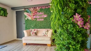 A room with a green wall, a beige sofa, and a sign that reads "Central Boutique Hotel Aruba". - Central Boutique Hotel (Oranjestad)