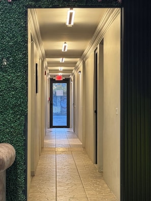 A hallway with a green wall, a tiled floor, and a door at the end.