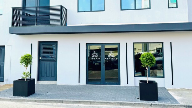 A modern building with a flat roof, large windows, and a balcony with metal railings. - Central Boutique Hotel (Oranjestad)