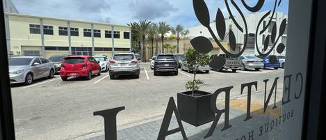 Un estacionamiento con varios coches, un edificio al fondo y un cartel con el texto "CENTRAL BOULEVARD HOTEL".
