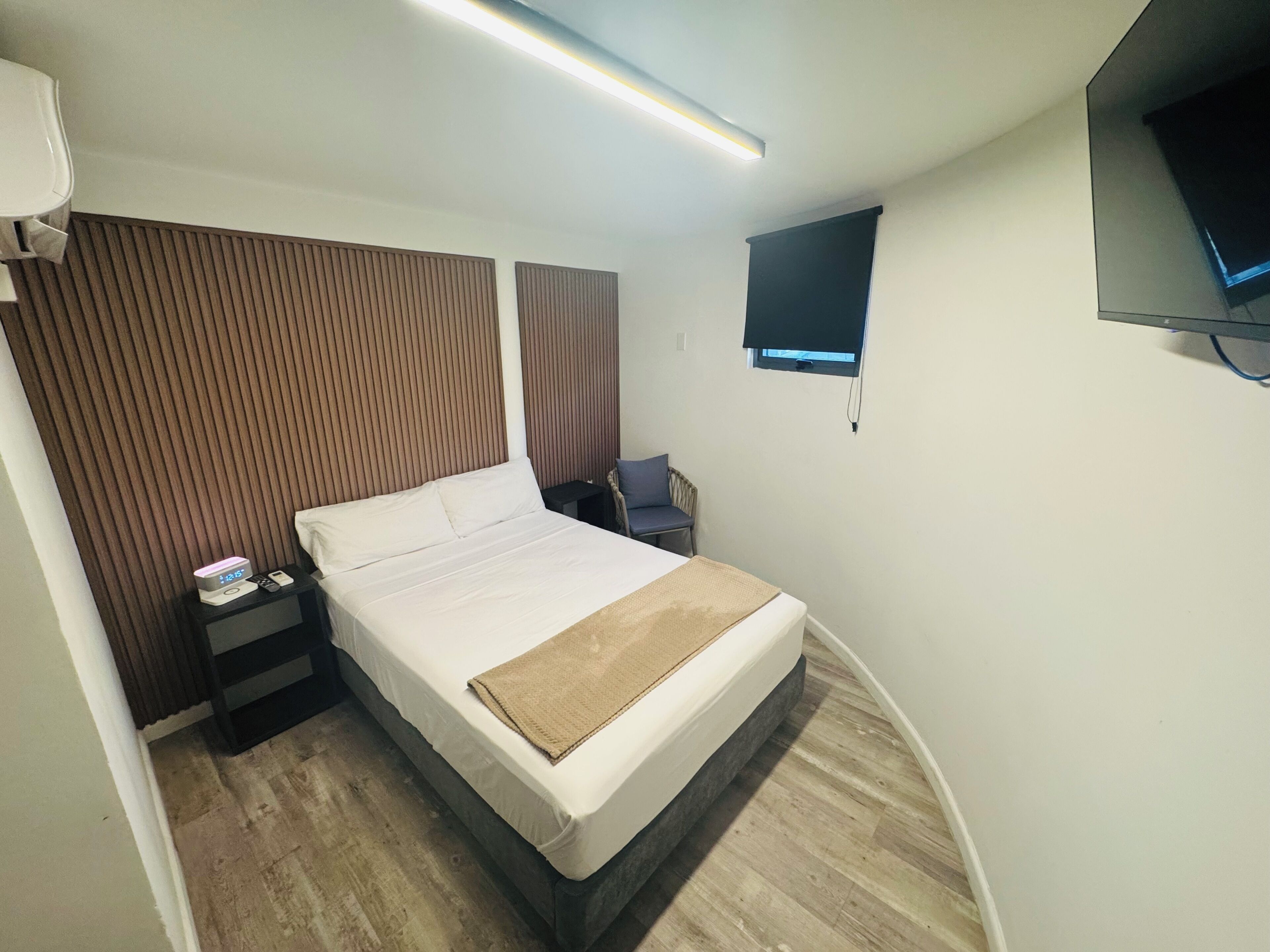 Una habitación de hotel con cama, mesita de noche, televisión y ventana.