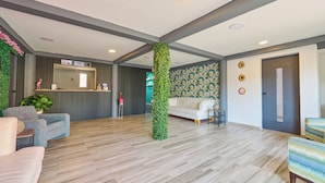 A spacious lobby with a reception desk, a white sofa, and a wooden floor. - Central Boutique Hotel (Oranjestad)