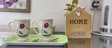 A kitchen counter with two decorative cups, a coffee maker, and a sign that reads "HOME Sweet HOME".