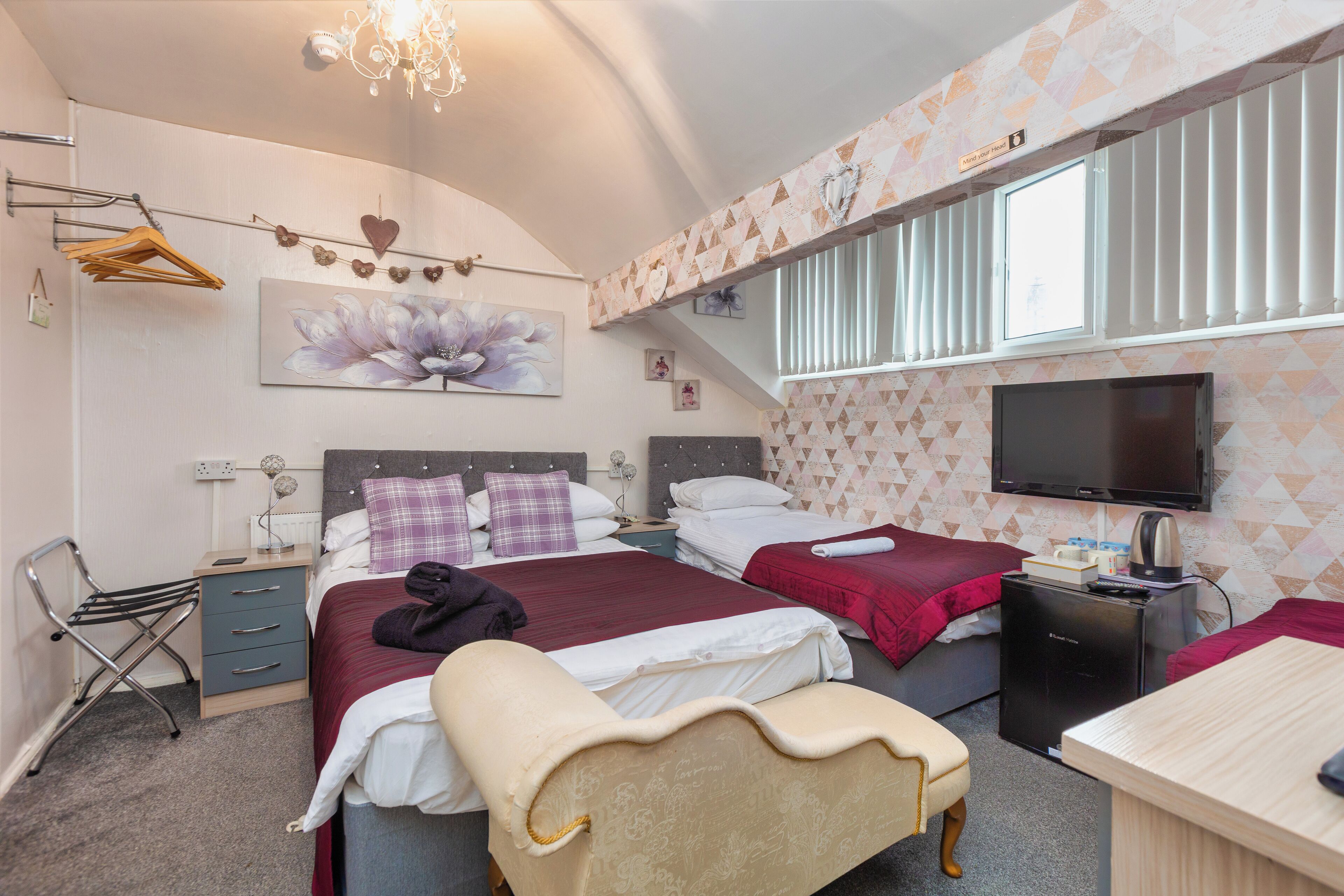 A hotel room with two beds, a TV, a desk, and a chair.