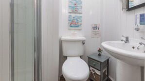 A bathroom with a toilet, sink, and a glass shower enclosure. - Friends Hotel (Blackpool)