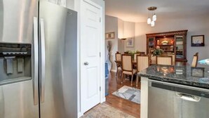 Una cocina con refrigerador de acero inoxidable, lavavajillas y un comedor con mesa y sillas de madera.