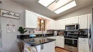 Una cocina moderna con armarios blancos, una isla central, un microondas, un horno y un lavavajillas.