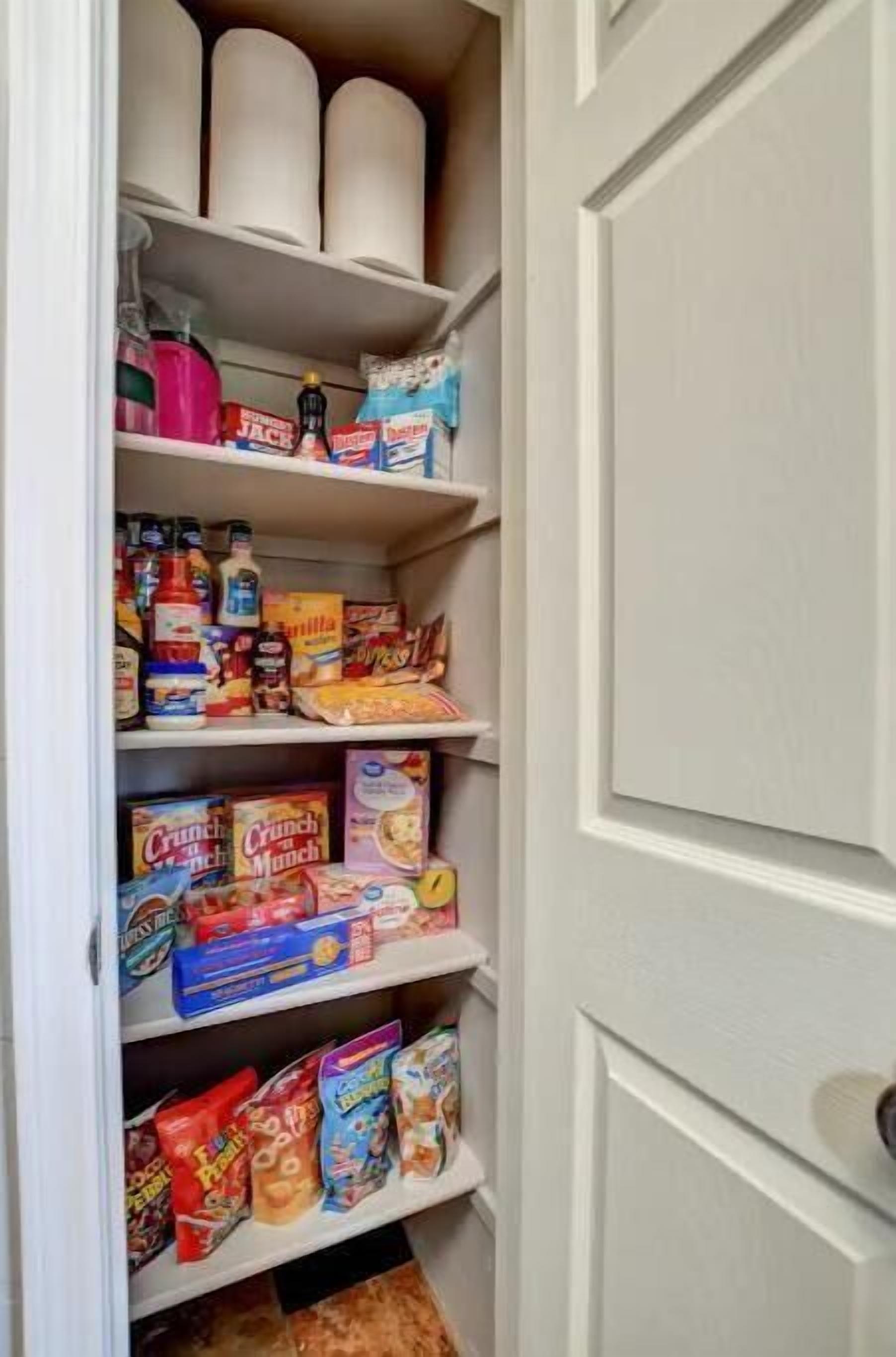 Een voorraadkast met planken vol met diverse levensmiddelen, waaronder ontbijtgranen, snacks en bakbenodigdheden.