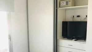 A bedroom with a bed, a wardrobe, a television, and a window.