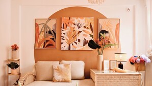 A cozy living room with a sofa, decorative pillows, a side table with a lamp, and wall art. - Stay at Casa Carnaval walking distance to Playa Moreno (Pampatar)