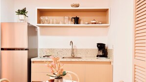 A modern kitchen with a stainless steel refrigerator, a coffee maker, and a sink. There is a dining table with a vase of flowers and a plate of food. - Stay at Casa Carnaval walking distance to Playa Moreno (Pampatar)