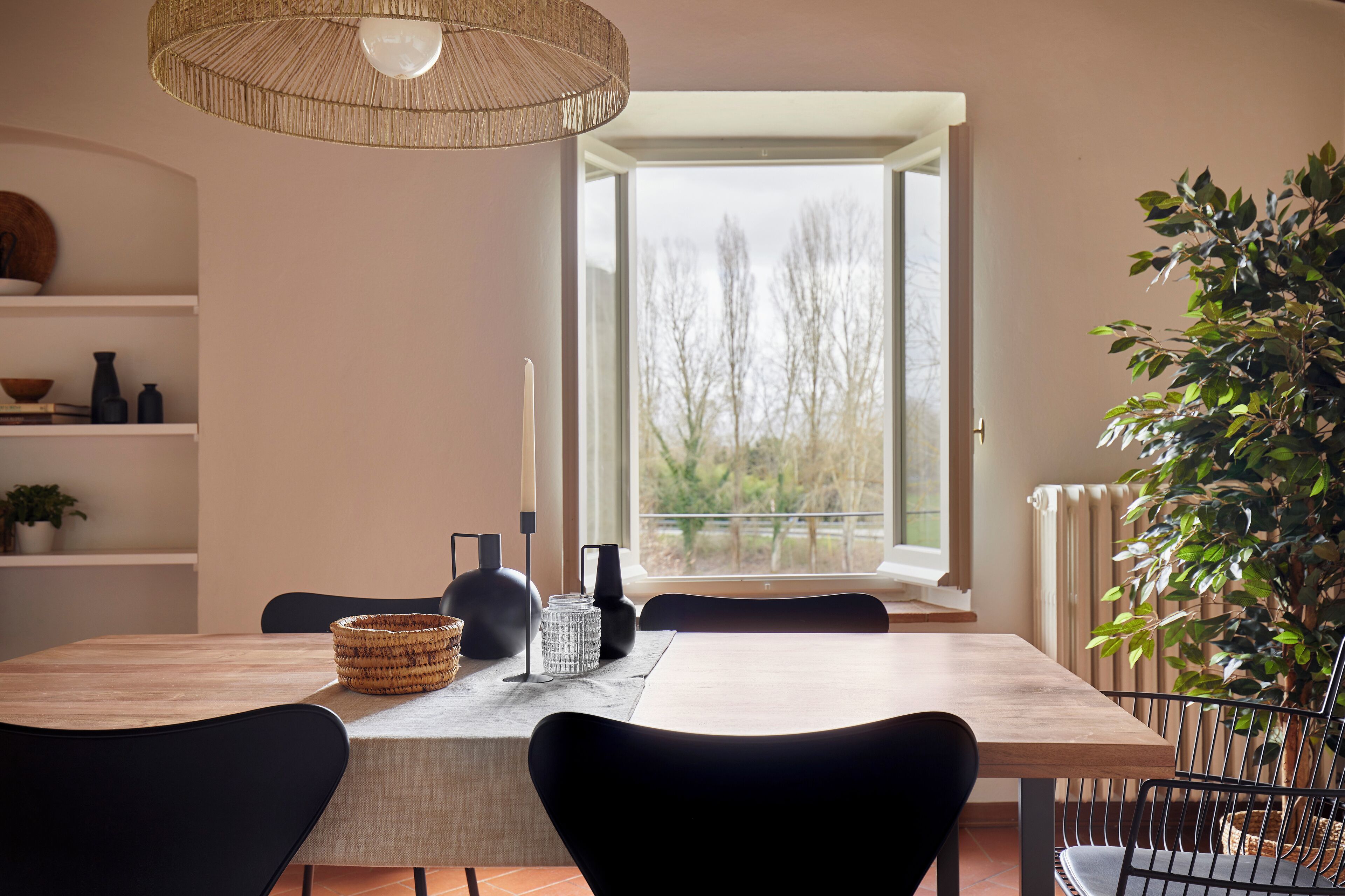 A dining area with a wooden table, black chairs, a woven basket, and a candle holder.