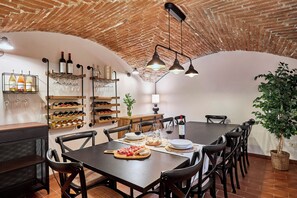 A dining area with a brick ceiling, wooden tables, and chairs. There are wine bottles and glasses on shelves. - Agriturismo Borgo Scaffaia (Scarperia e San Piero)