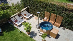 Terraza en la azotea con sillones de descanso, jacuzzi y plantas en macetas.