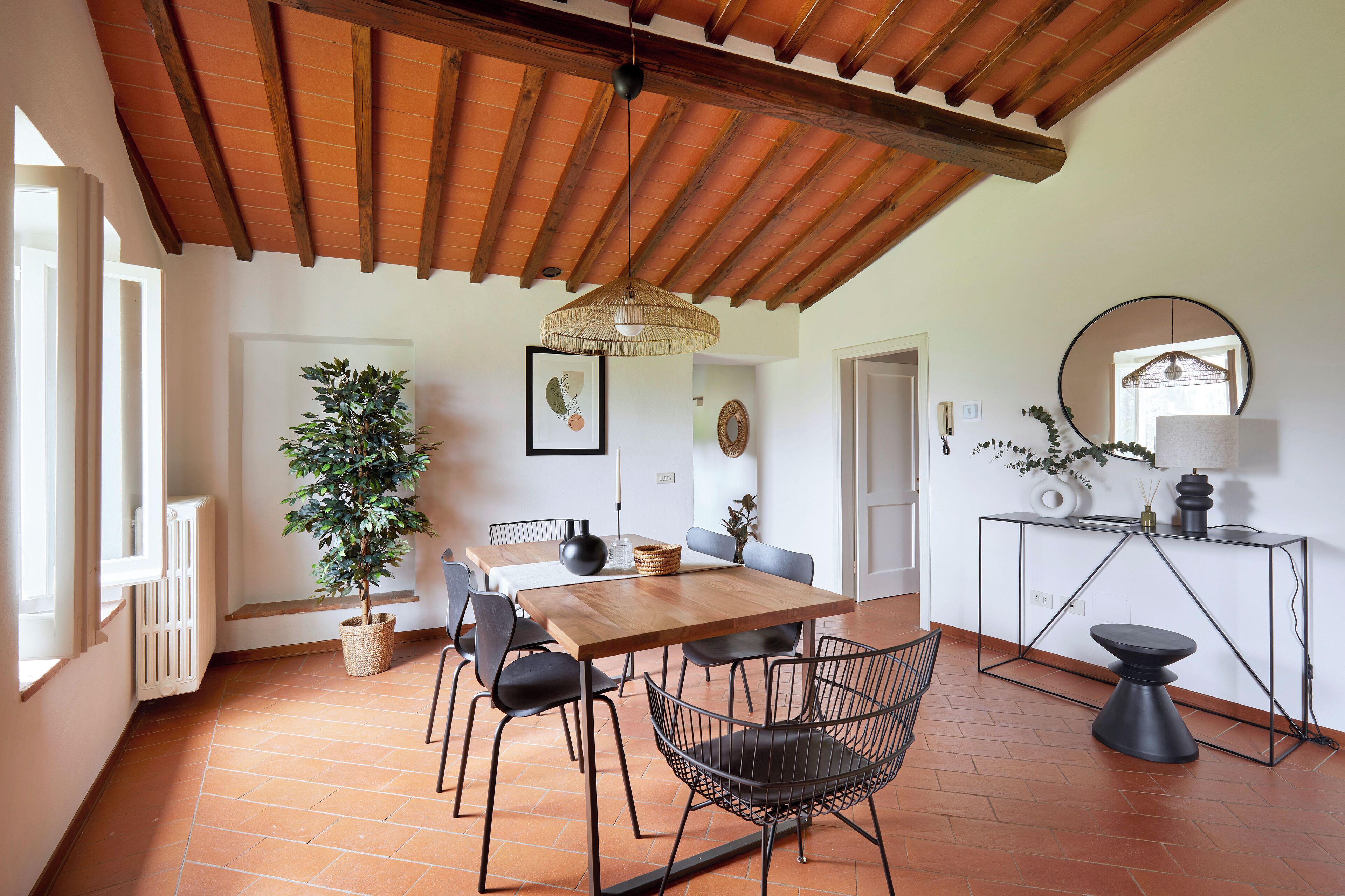 Un comedor con mesa de madera, sillas negras y una lámpara colgante.