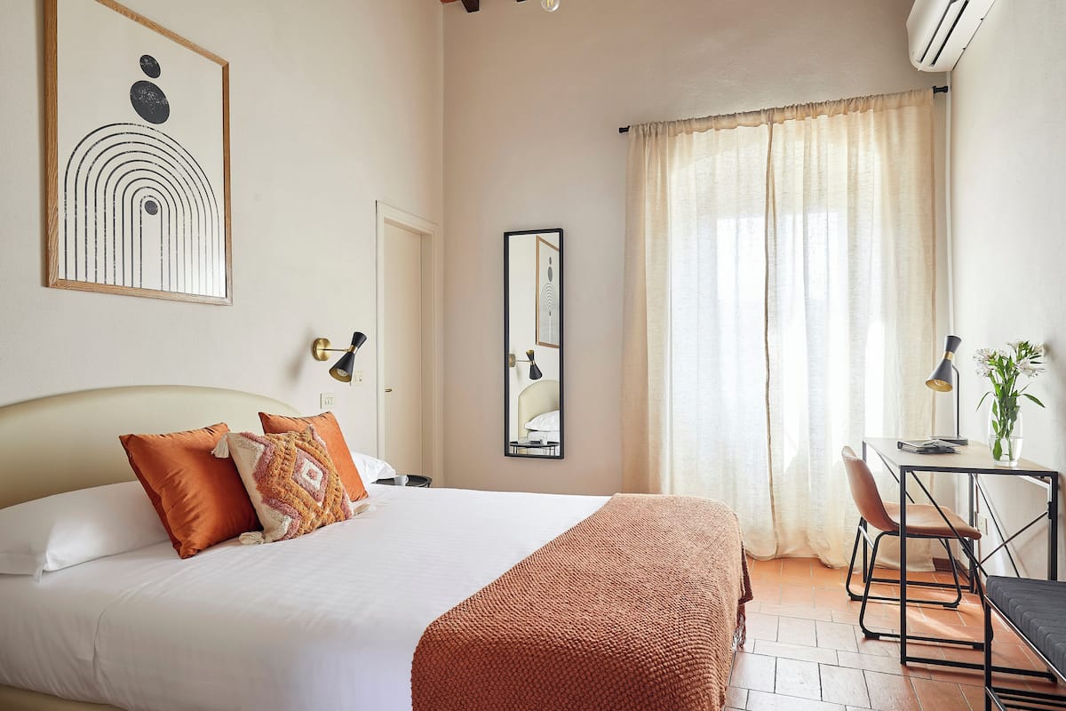 A hotel room with a bed, a desk, and a chair.