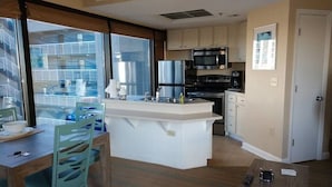 Una cocina moderna con armarios blancos, una isla central y un comedor con mesa y sillas.