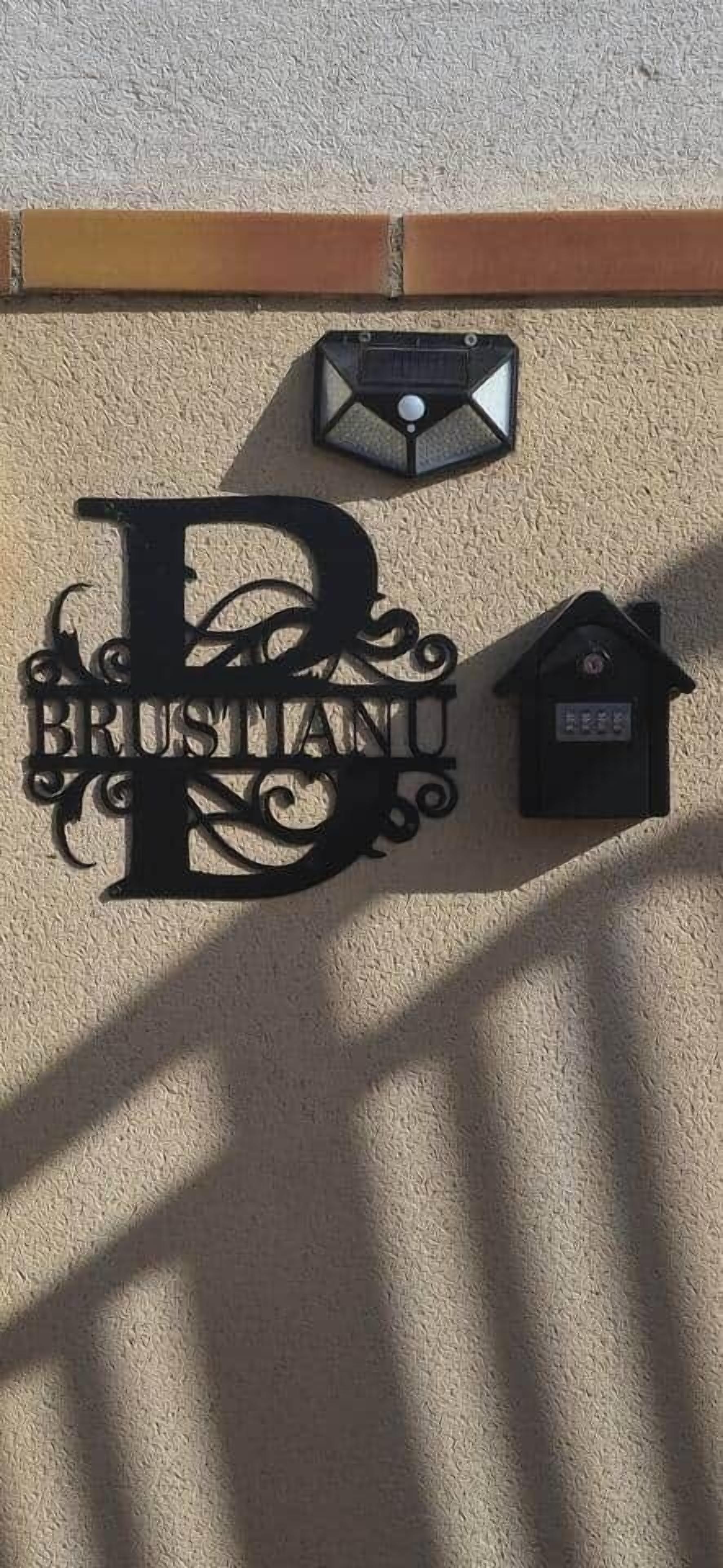 A wall-mounted sign with the word "BRUSTIANO" in large letters, a small house-shaped object, and a mailbox.
